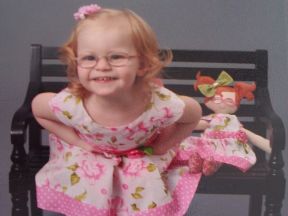 toddler girl in glasses for farsightedness with her doll who also wears glasses