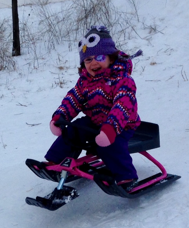 girl wearing an eye patch on a sled